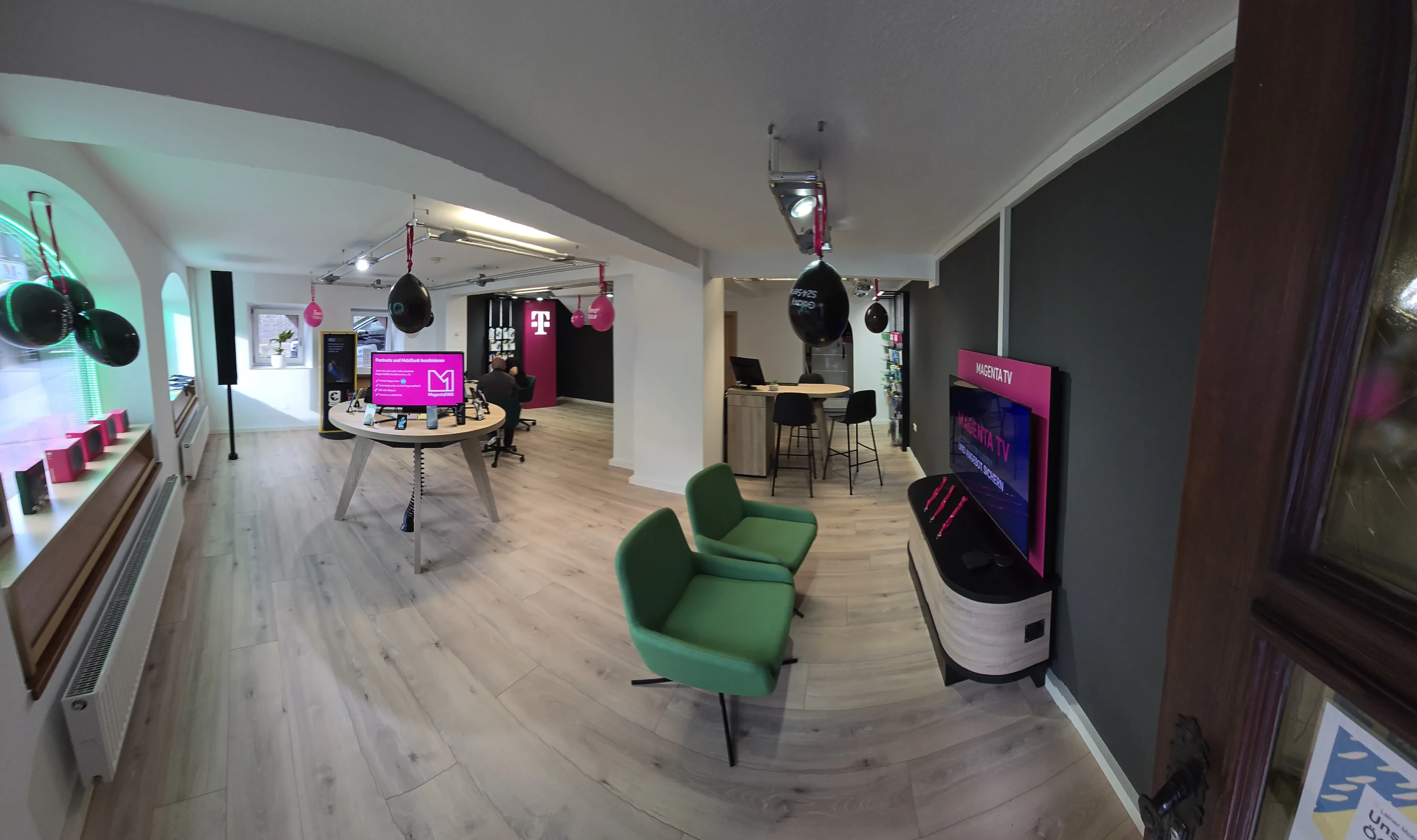 Telekom Shop Innenansicht mit Smartphone-Tisch, MagentaTV-Display und Sitzbereich